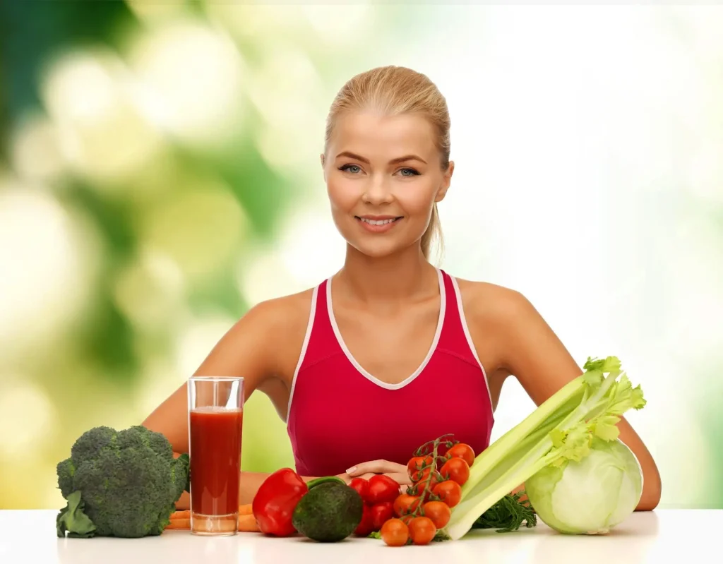 A woman smiling with various vegetables and healthy eatables in placed in front of her.